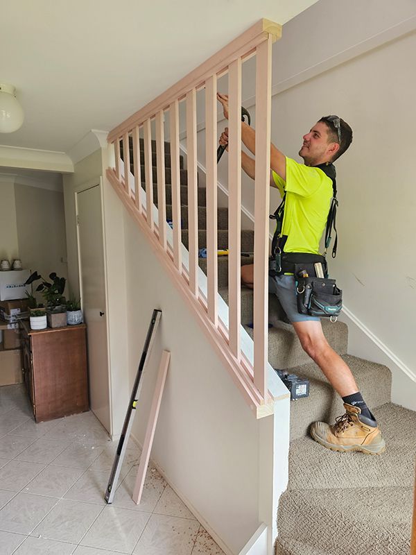A Man Is Working On A Railing On A Set Of Stairs — Coffs Coast Building Pty Ltd in Toormina, NSW