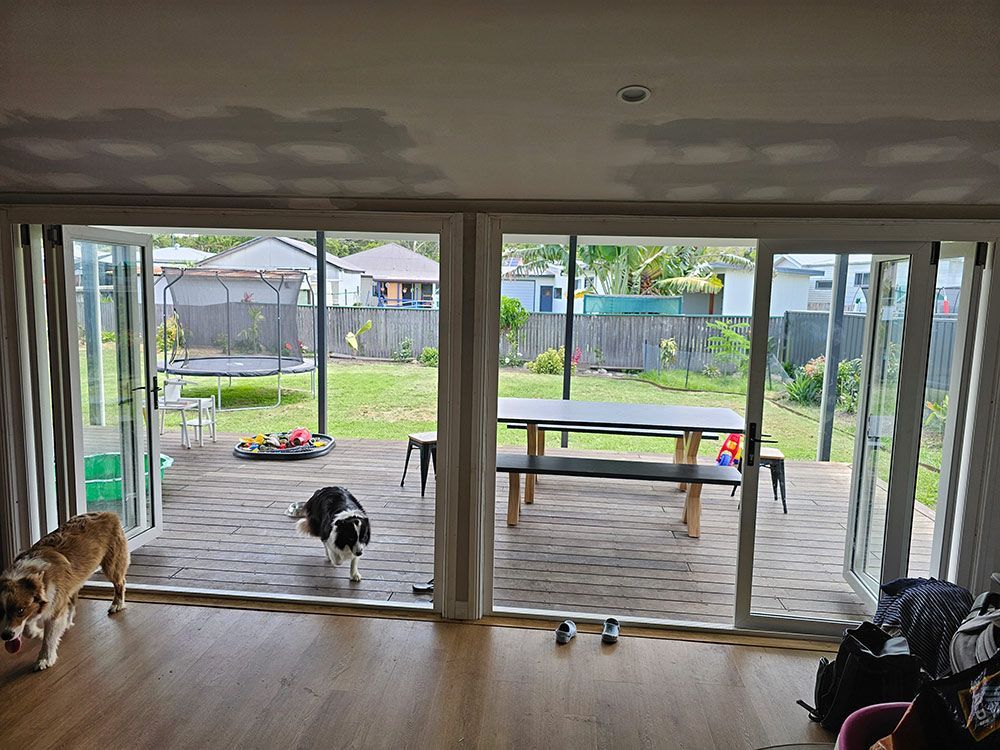 A Dog Is Standing On A Wooden Deck In A Living Room — Coffs Coast Building Pty Ltd in Toormina, NSW
