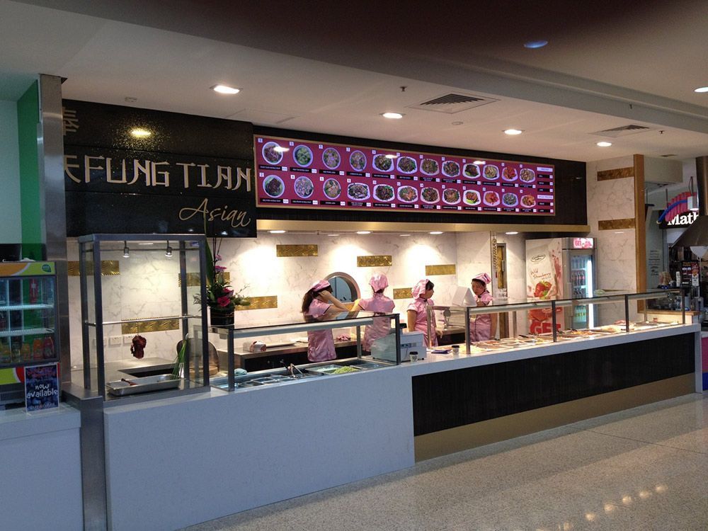 A Group Of People Standing Behind A Counter In A Restaurant — Coffs Coast Building Pty Ltd in Toormina, NSW