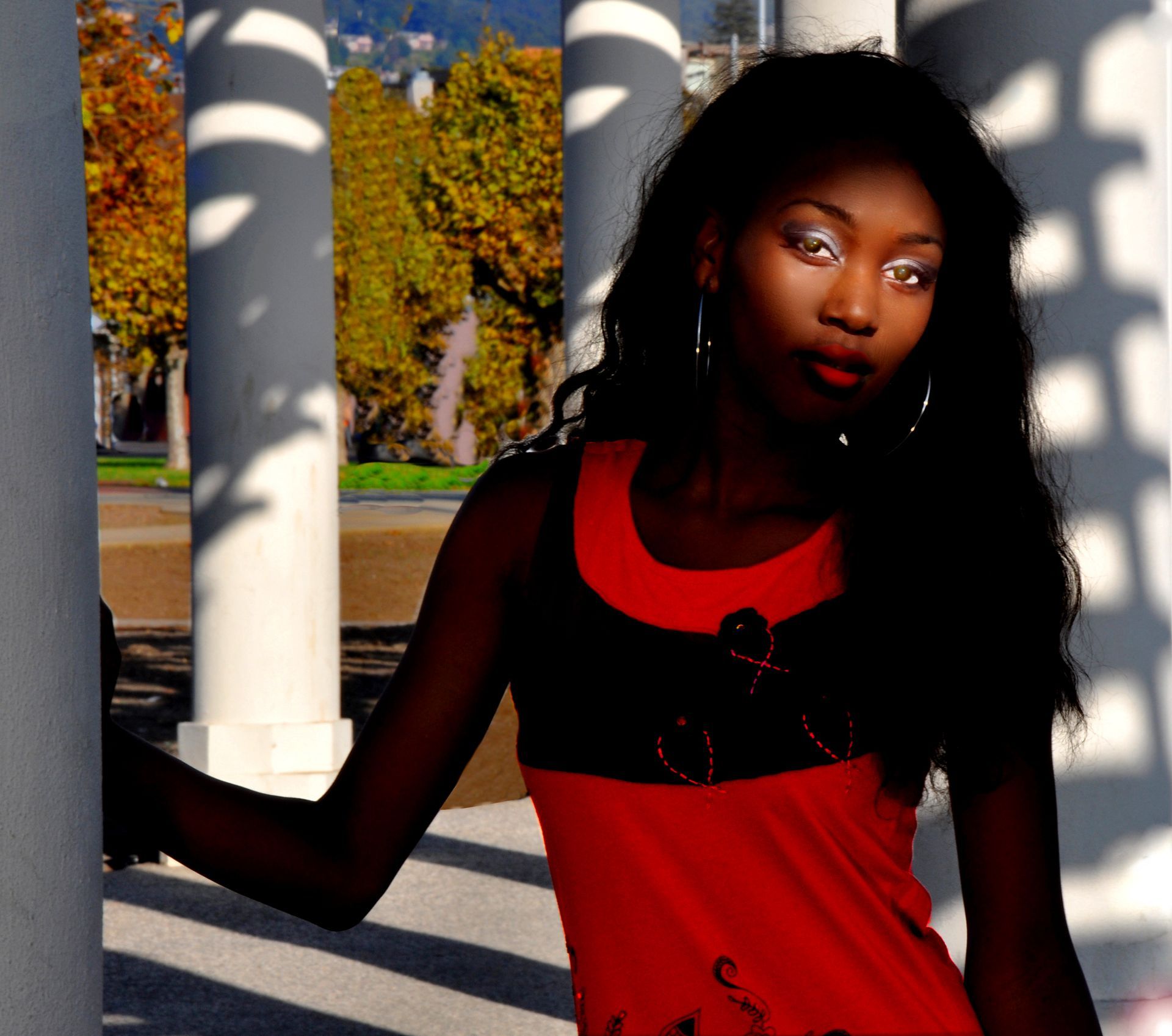 a woman in a red tank top stands in front of columns