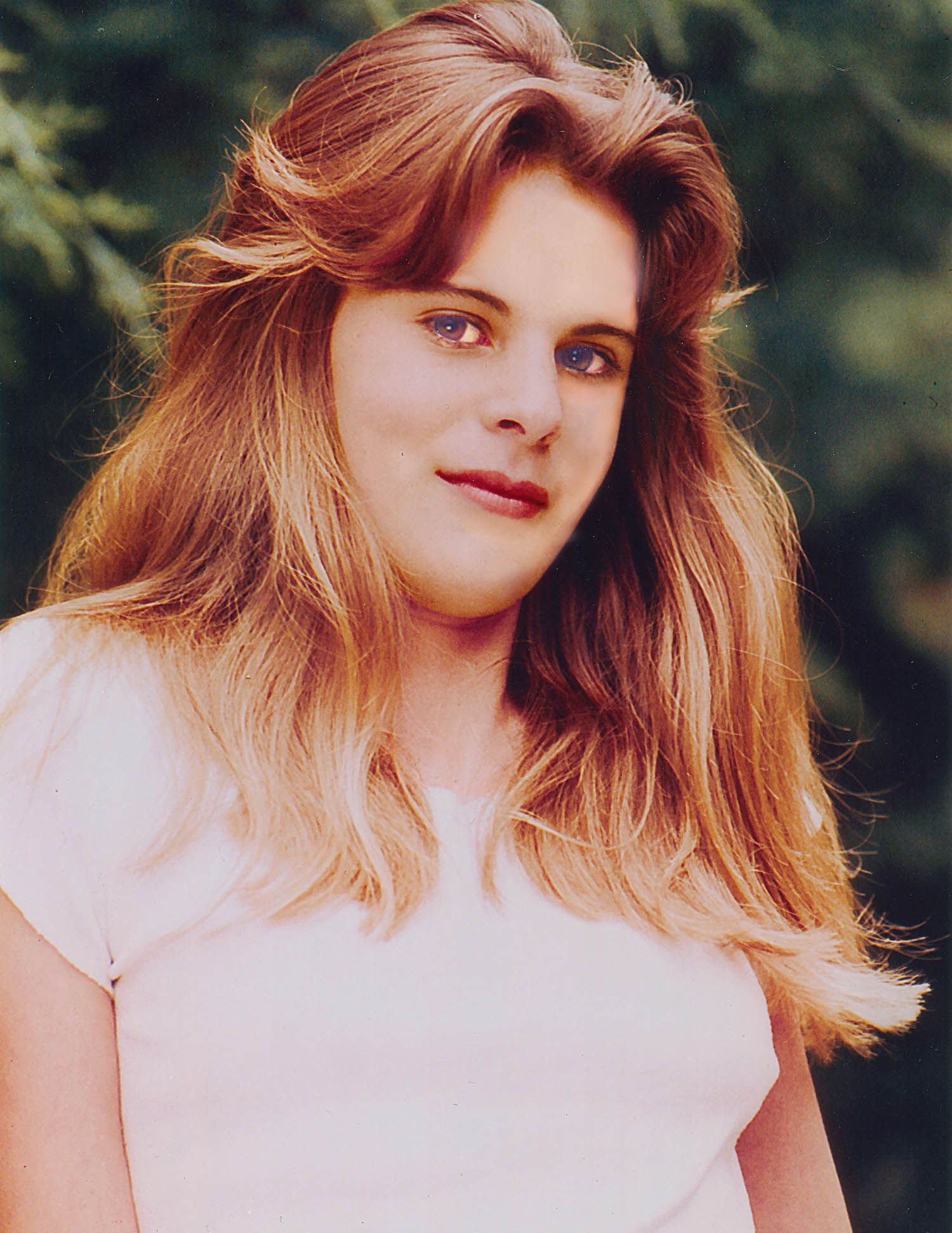 a woman with long hair and blue eyes is wearing a white shirt