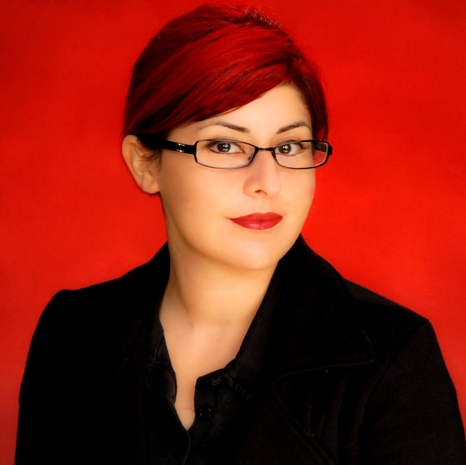 a woman with red hair wearing glasses and a black jacket