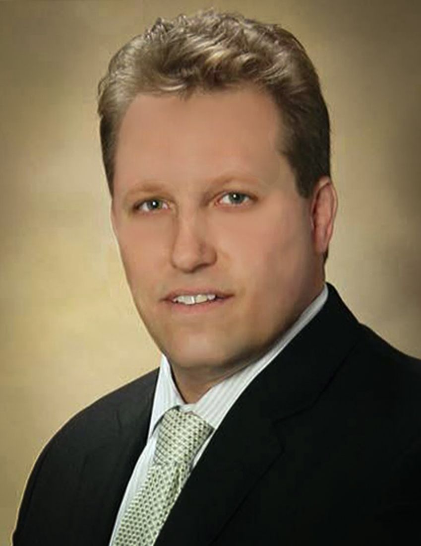 a man in a suit and tie is smiling for the camera .