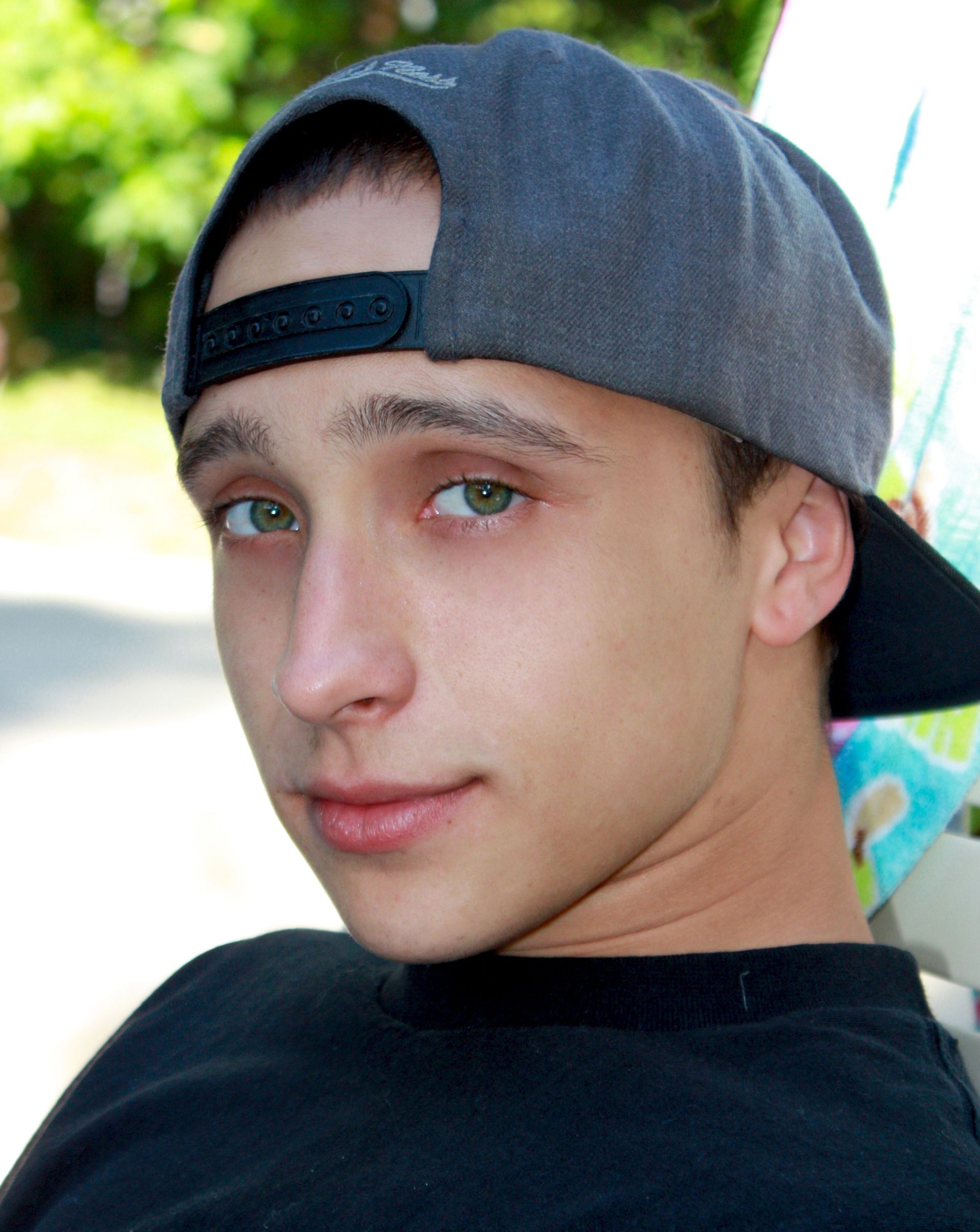 a young man wearing a baseball cap and a black shirt