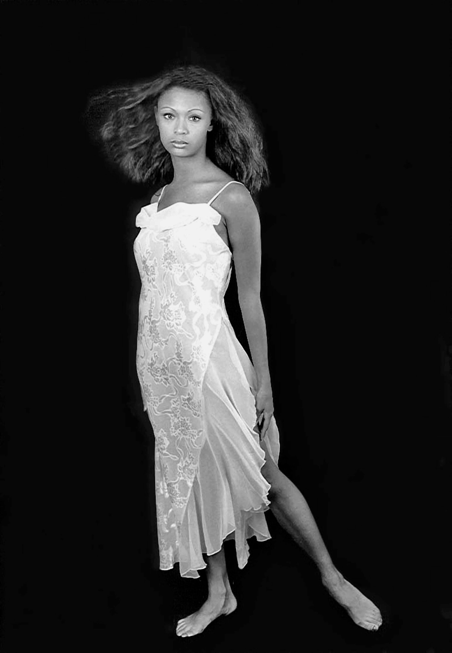 a woman in a white dress is standing in front of a black background .