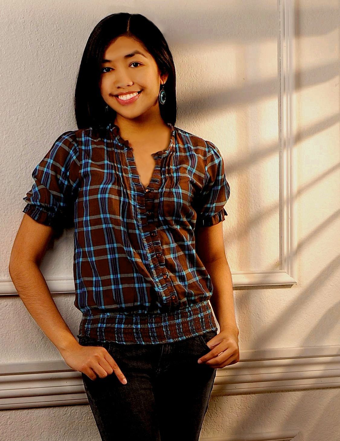 a woman in a plaid shirt is leaning against a wall