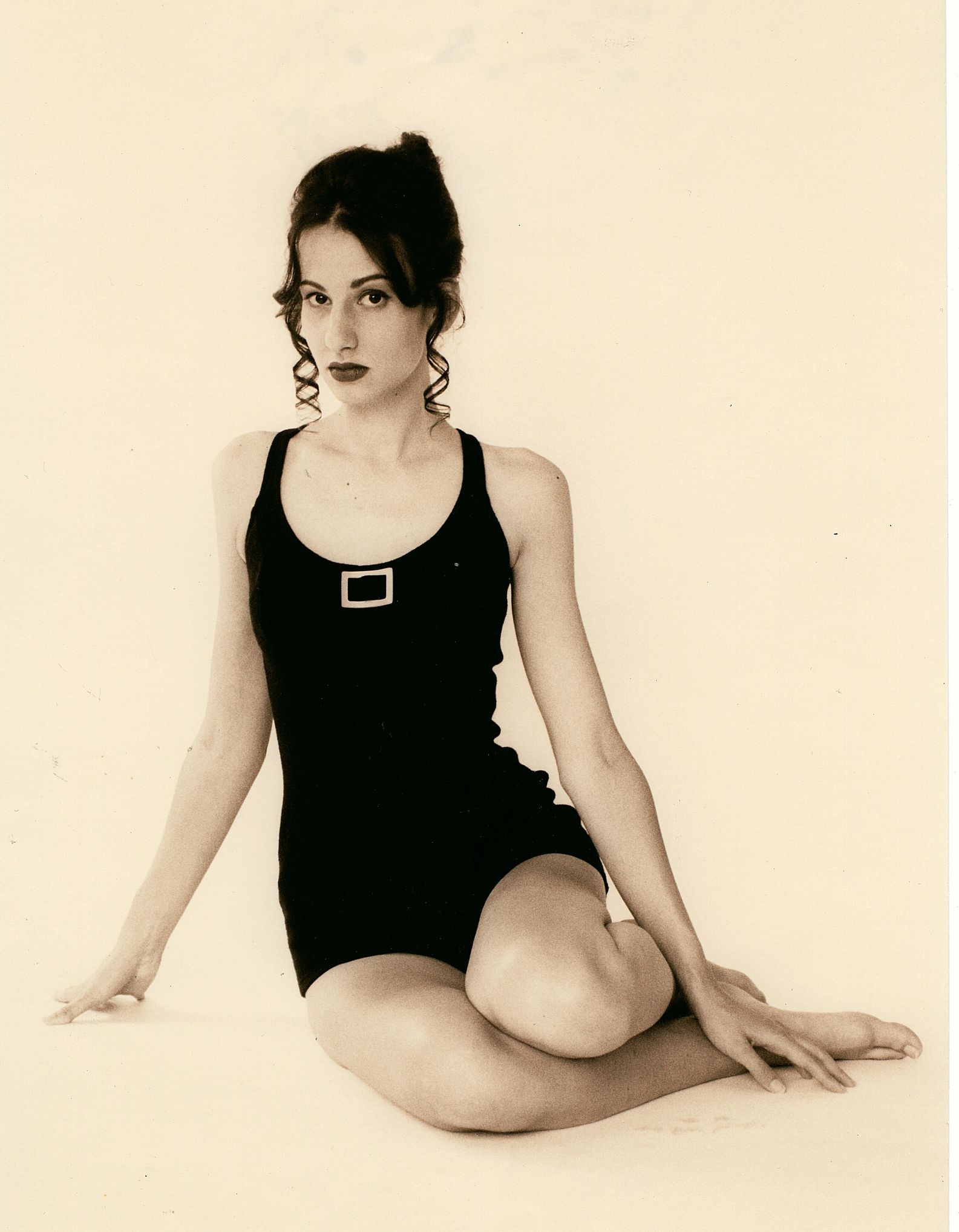 a woman in a black bathing suit sits on the floor