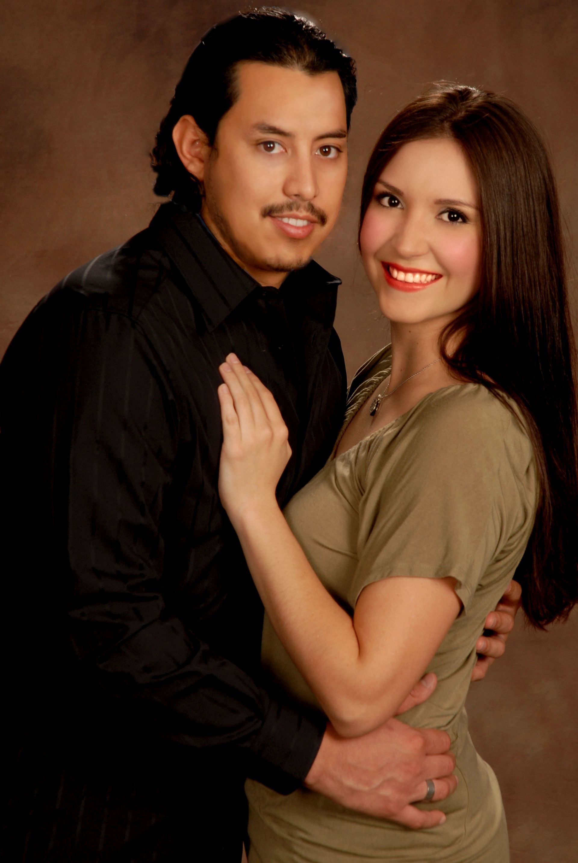 A man in a black shirt is hugging a woman in a green shirt