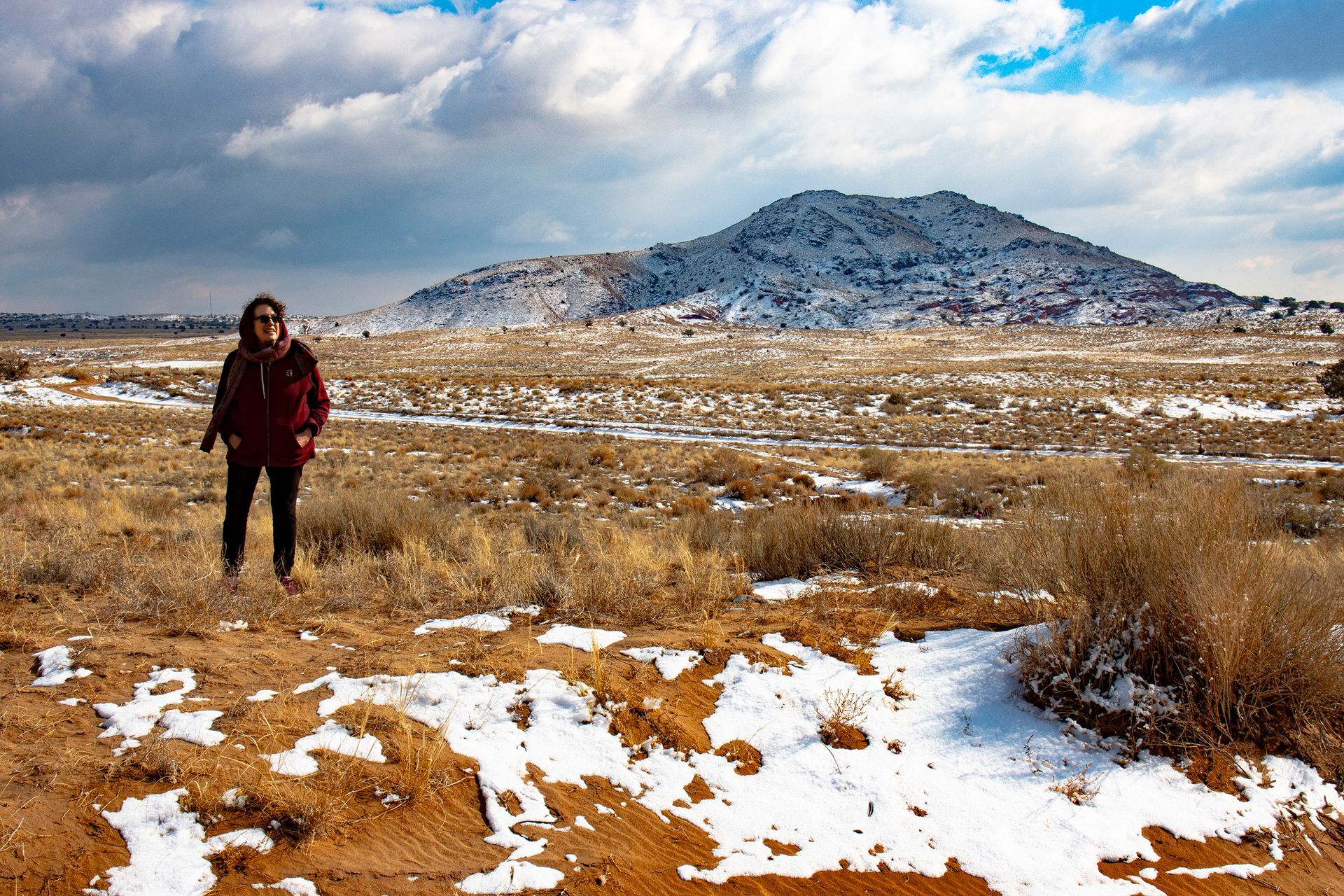 a woman is standing in a snowy field with a mountain in the background .