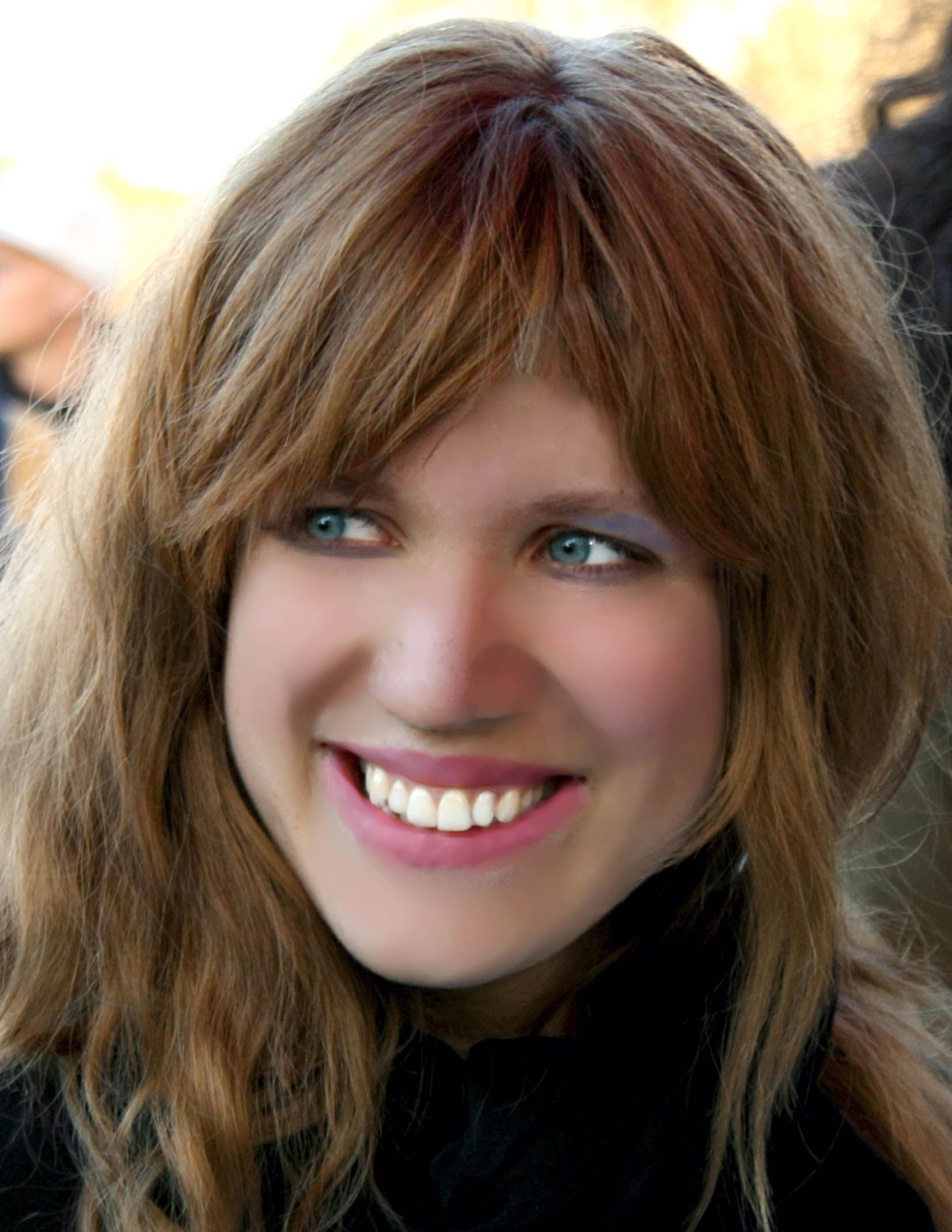 a woman with long brown hair and blue eyes is smiling