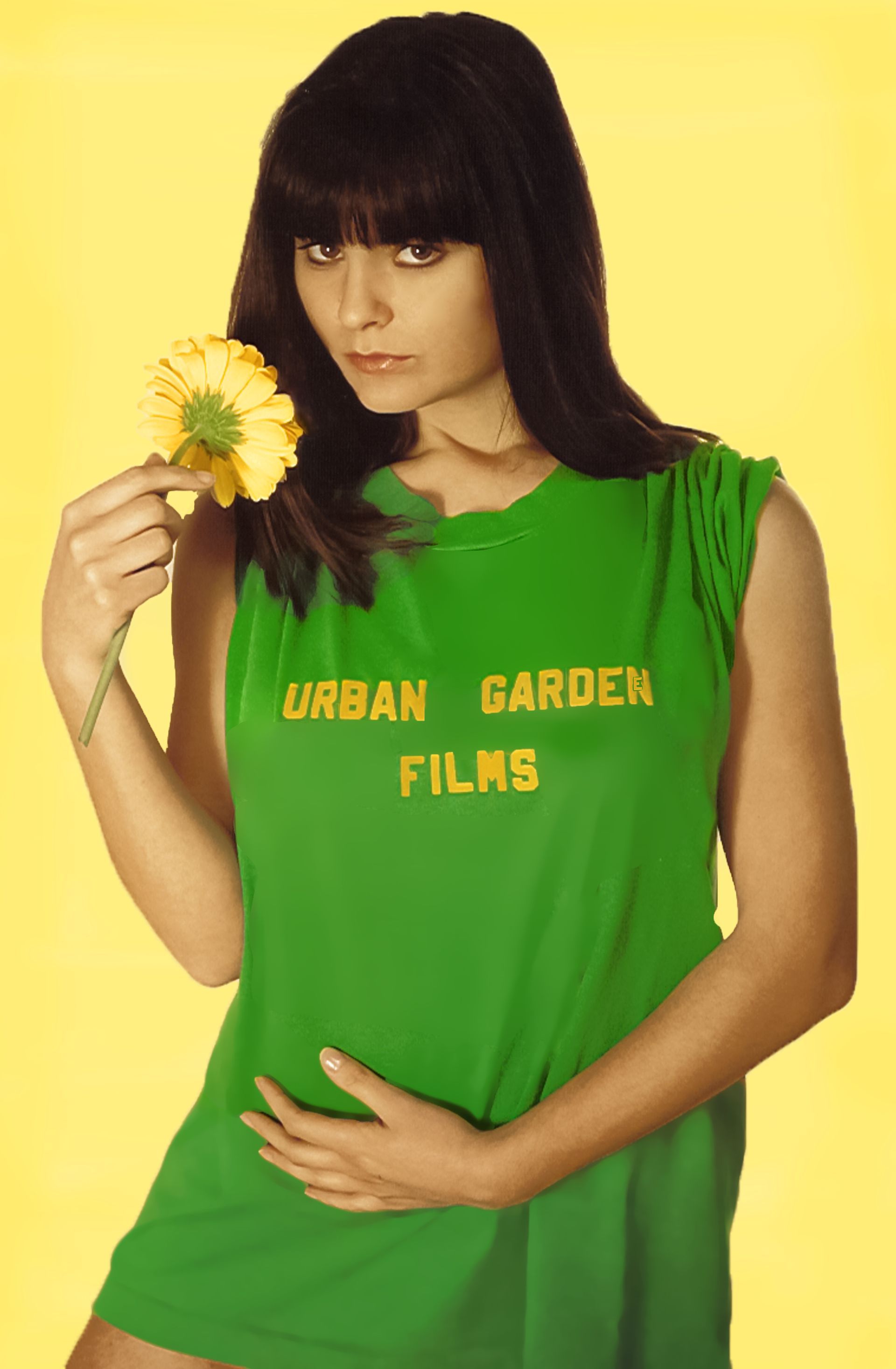 a woman in a green urban garden films shirt holds a flower