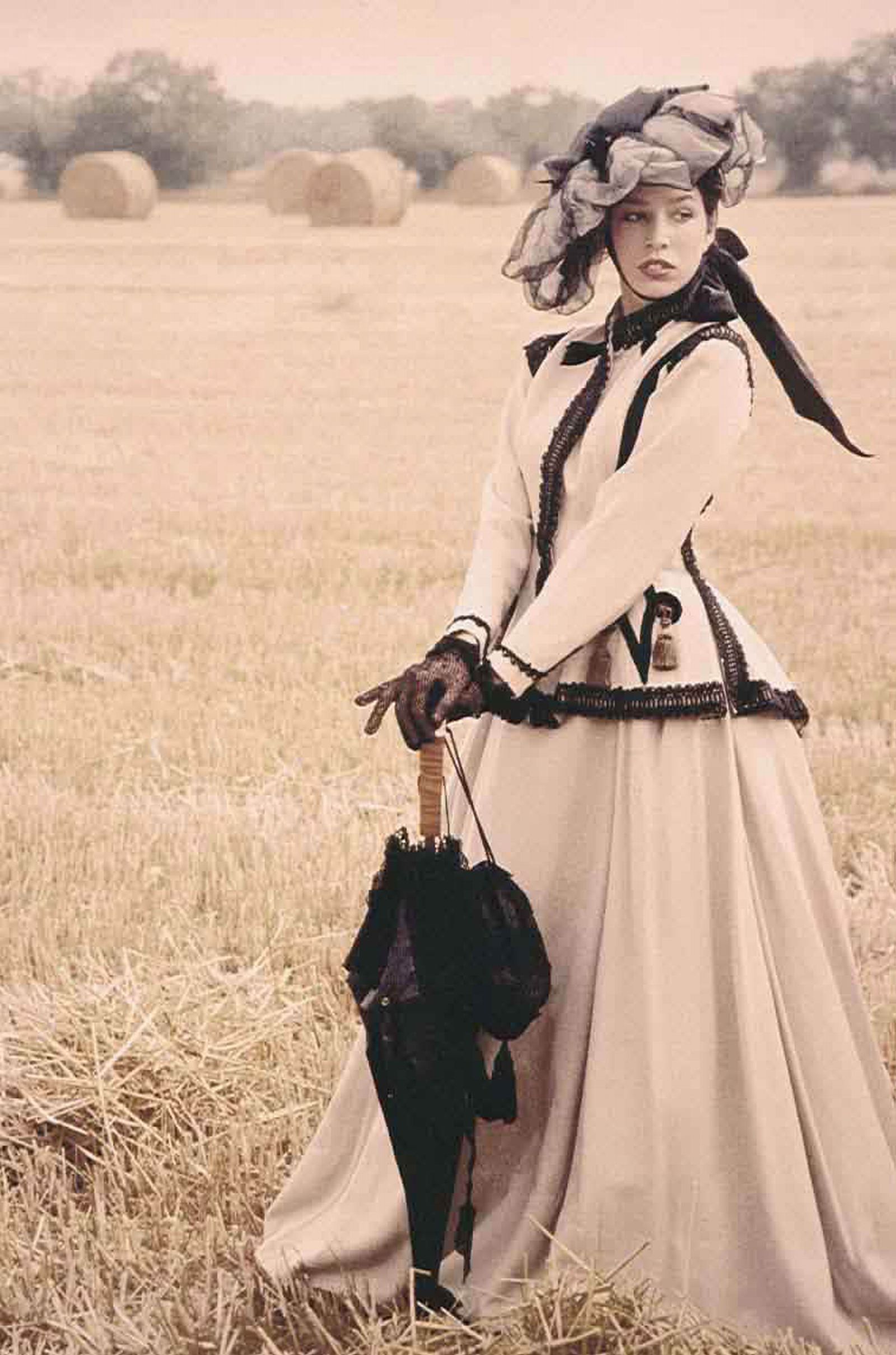 a woman in a white dress is holding an umbrella in a field