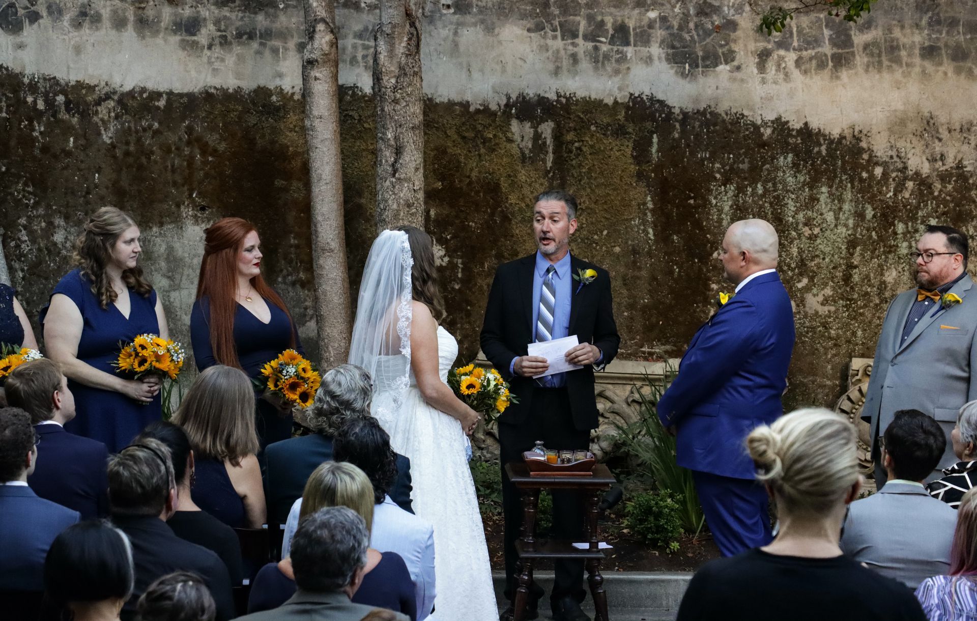 a bride and groom are getting married in front of a crowd of people .