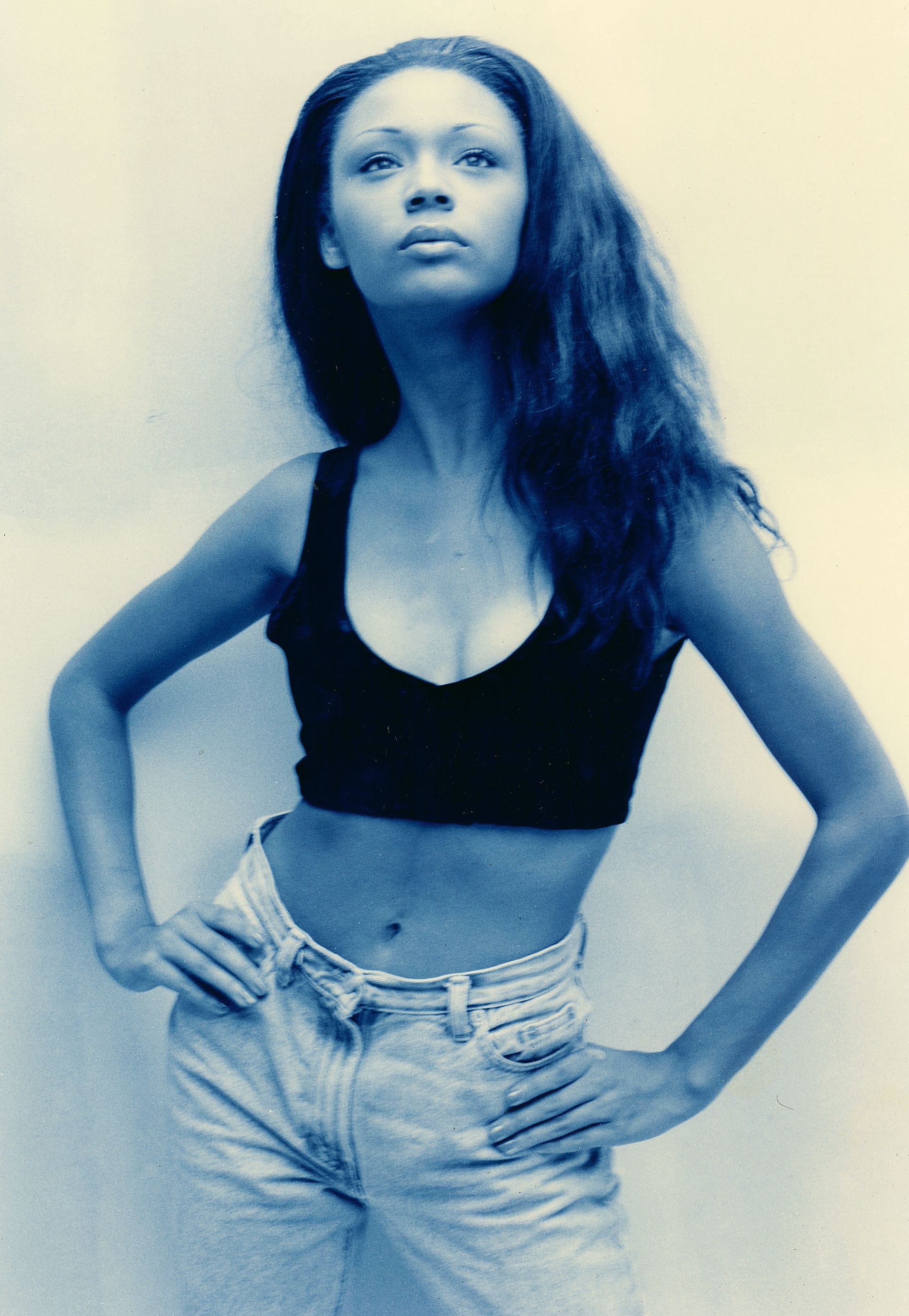 a woman in a black crop top and jeans stands with her hands on her hips