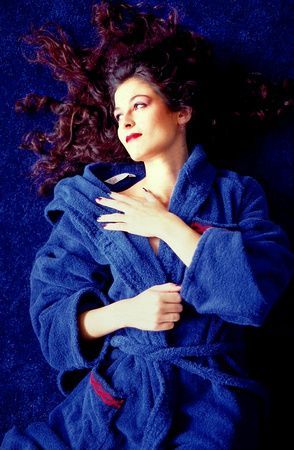 a woman in a blue robe is laying on the floor