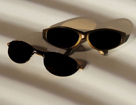 two pairs of sunglasses are sitting on a white surface
