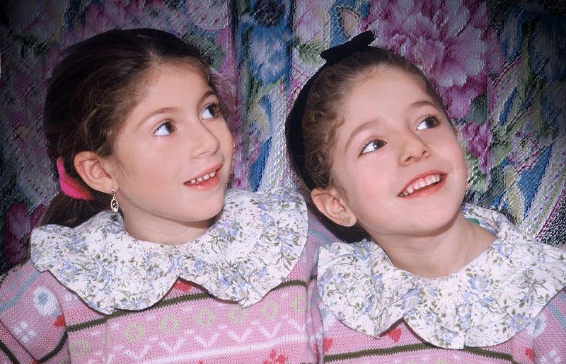two little girls are standing next to each other and smiling .