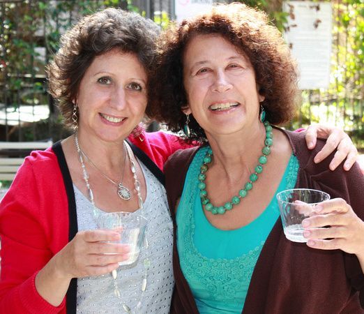 two women are posing for a picture and one is holding a glass of water