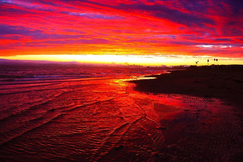 a colorful sunset over the ocean with a beach in the foreground