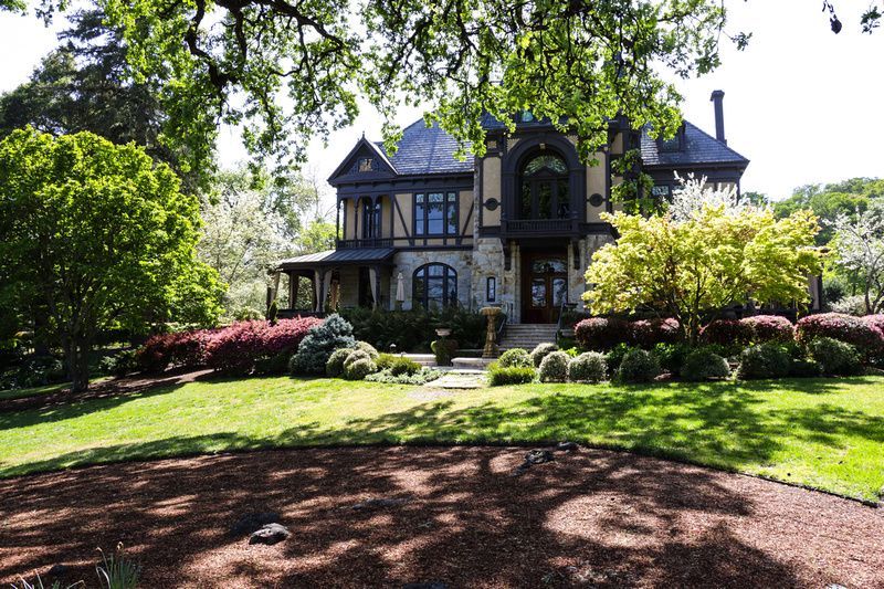 a large house sits in the middle of a lush green field