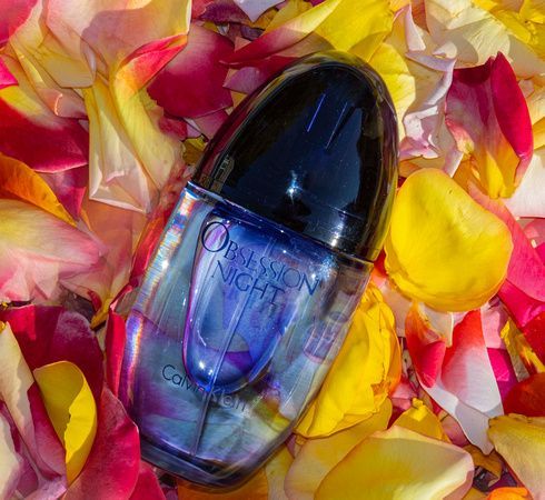 a bottle of perfume is sitting on top of a pile of rose petals .