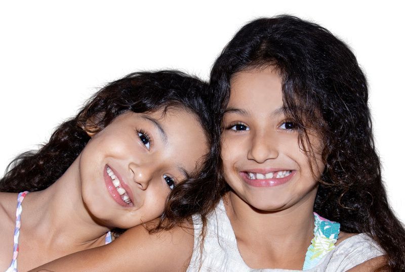two little girls are hugging each other and smiling for the camera .