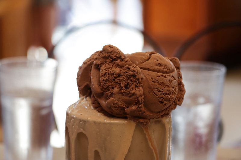 a scoop of chocolate ice cream is on top of a milkshake .