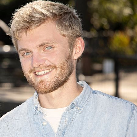 a young man with a beard is smiling for the camera while wearing a blue shirt .