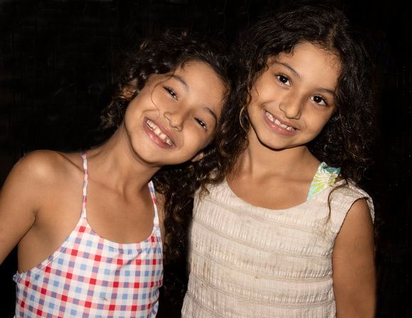Two little girls are posing for a picture together and smiling