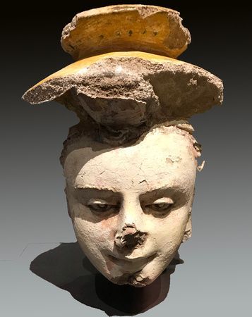 a statue of a woman 's head with a hat on top of it .