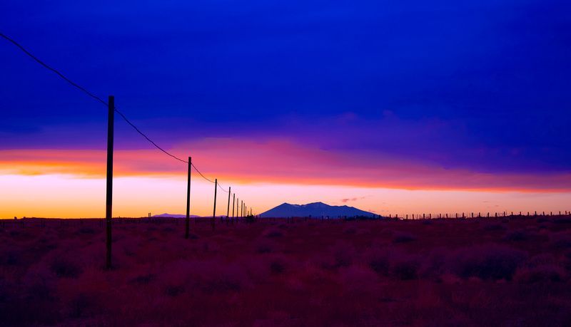 a sunset over a desert with a mountain in the distance .