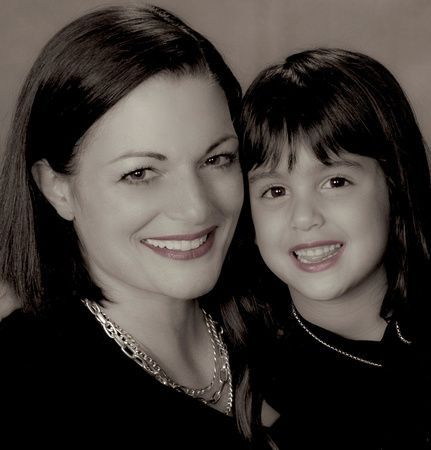 a woman and a little girl are posing for a picture and smiling for the camera .