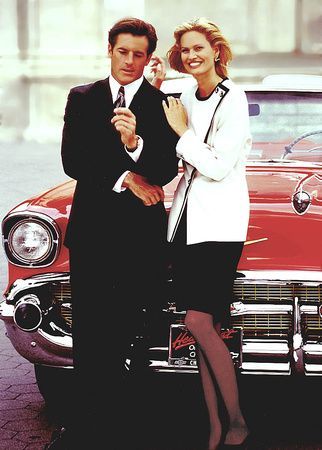 a man and a woman standing next to a red car