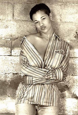 a woman in a striped shirt is standing in front of a brick wall .