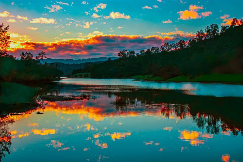 a lake with a sunset in the background and trees reflected in the water .
