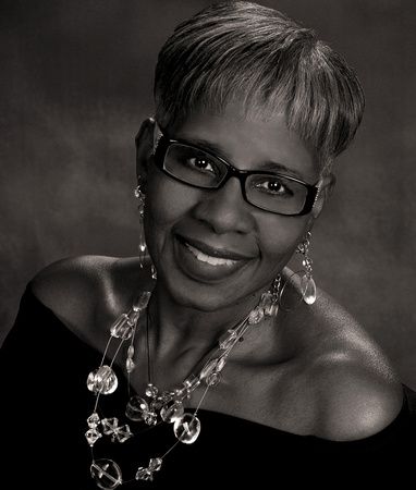 a black and white photo of a woman wearing glasses and a necklace