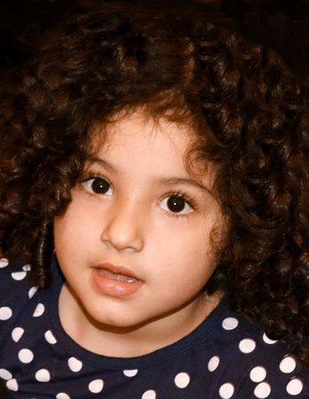 a little girl with curly hair is wearing a polka dot shirt .