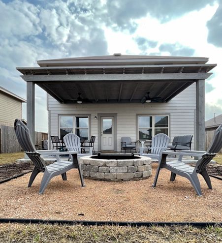 Outdoor gravel patio with stone fire pit and lawn chairs