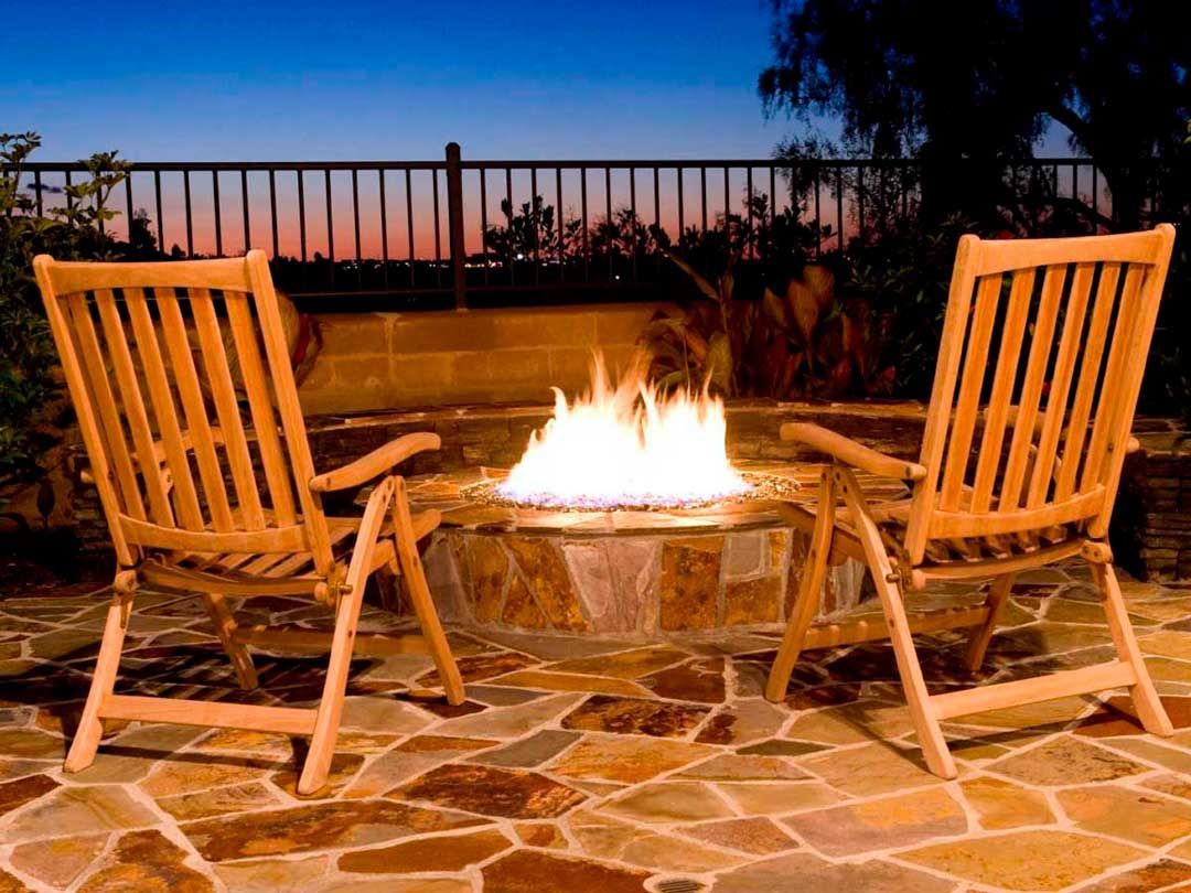 Small outdoor space with a stone wood-burning fire pit and chairs