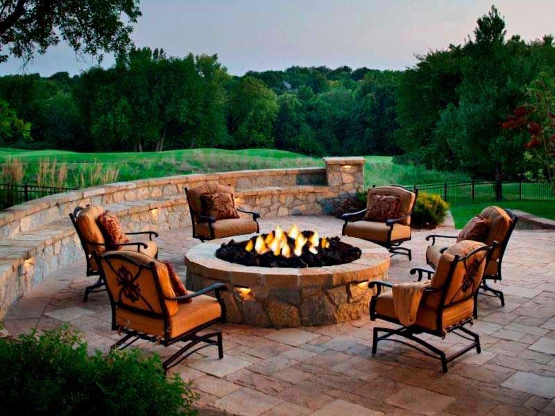 An outdoor patio made of limestone with a fire pit and luxurious chairs