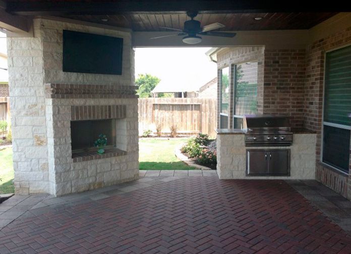 Wood-covered ceiling patio with fireplace and kitchen