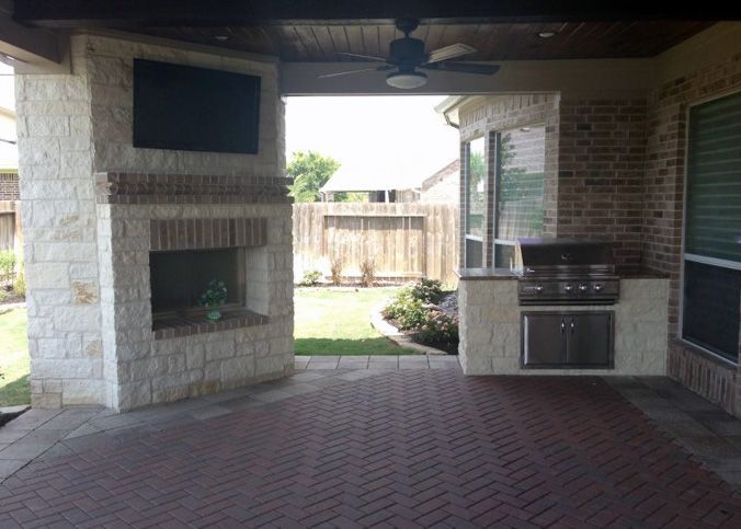 Wood-covered ceiling patio with fireplace and kitchen