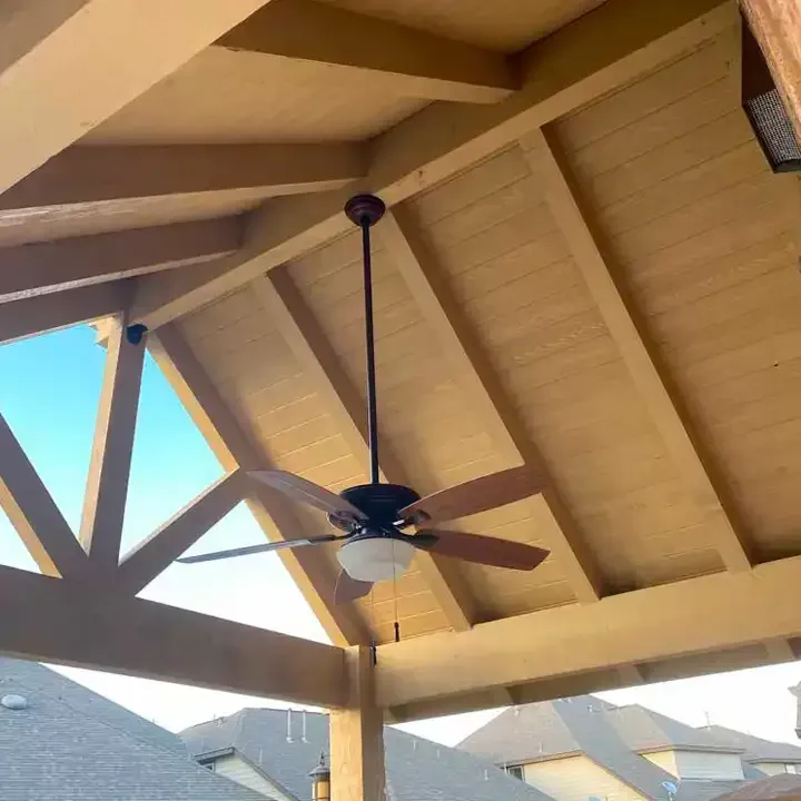 A ceiling fan is hanging from the ceiling of a wooden structure.