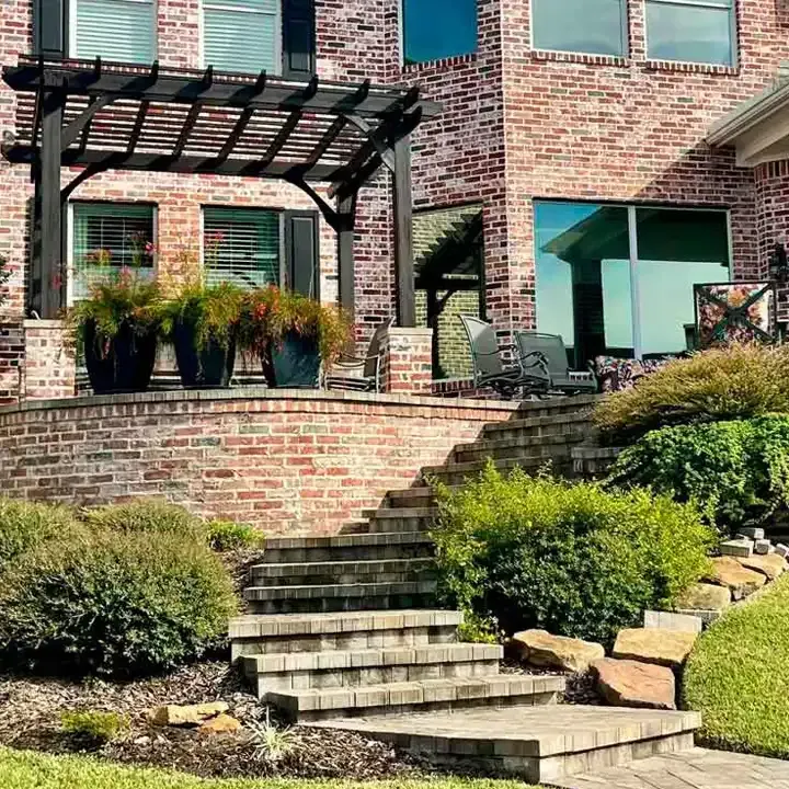 A brick house with a pergola and stairs in front of it.