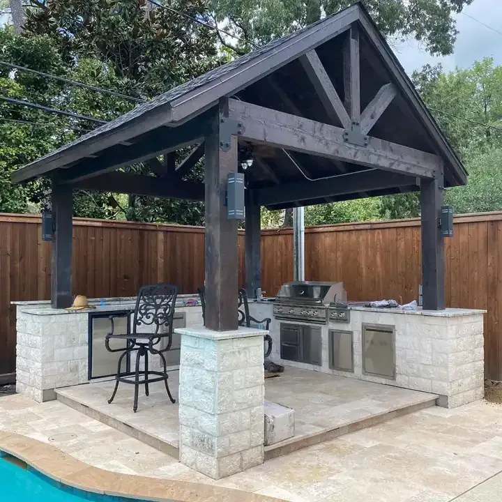 A wooden gazebo with a grill underneath it.