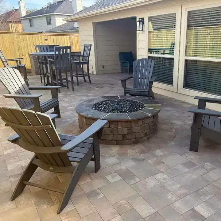 There is a fire pit on the patio with chairs around it.