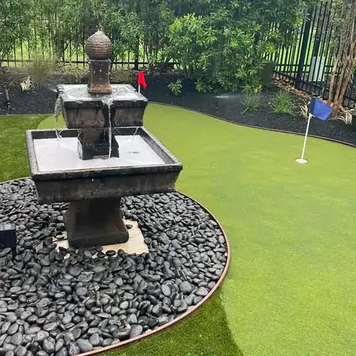 There is a fountain in the middle of a golf course.