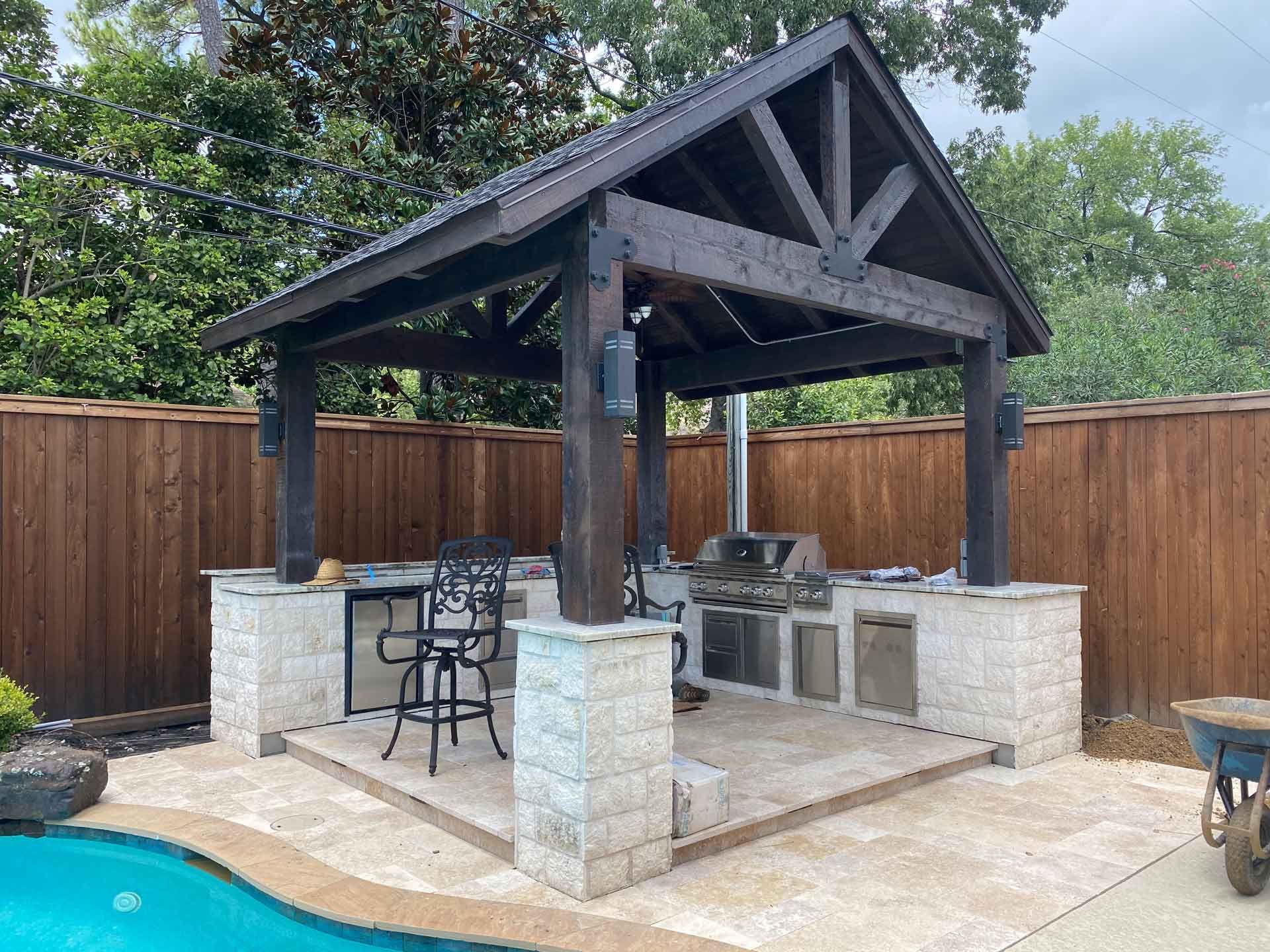Outdoor kitchen covered with cedar pergola and finished with marble tiles