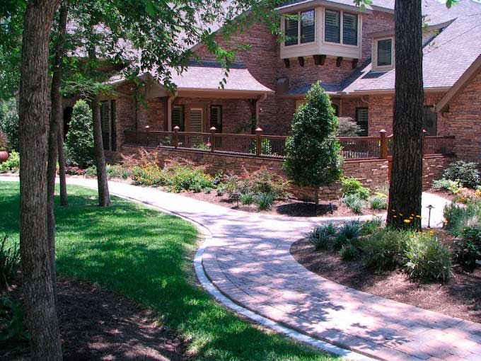 Red stone pathway surrounded by landscaping with plants and trees