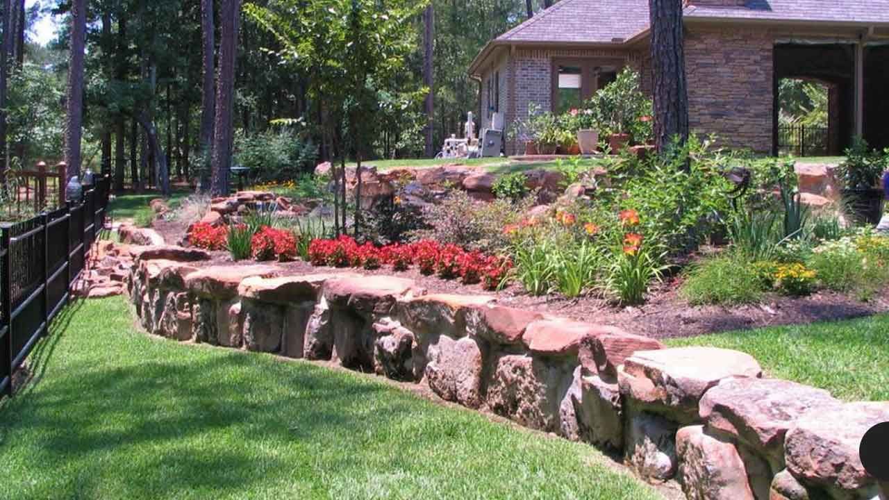 Landscaping with a large stone wall with flowers and plants